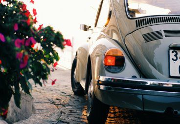 Classic car driving next to flowers