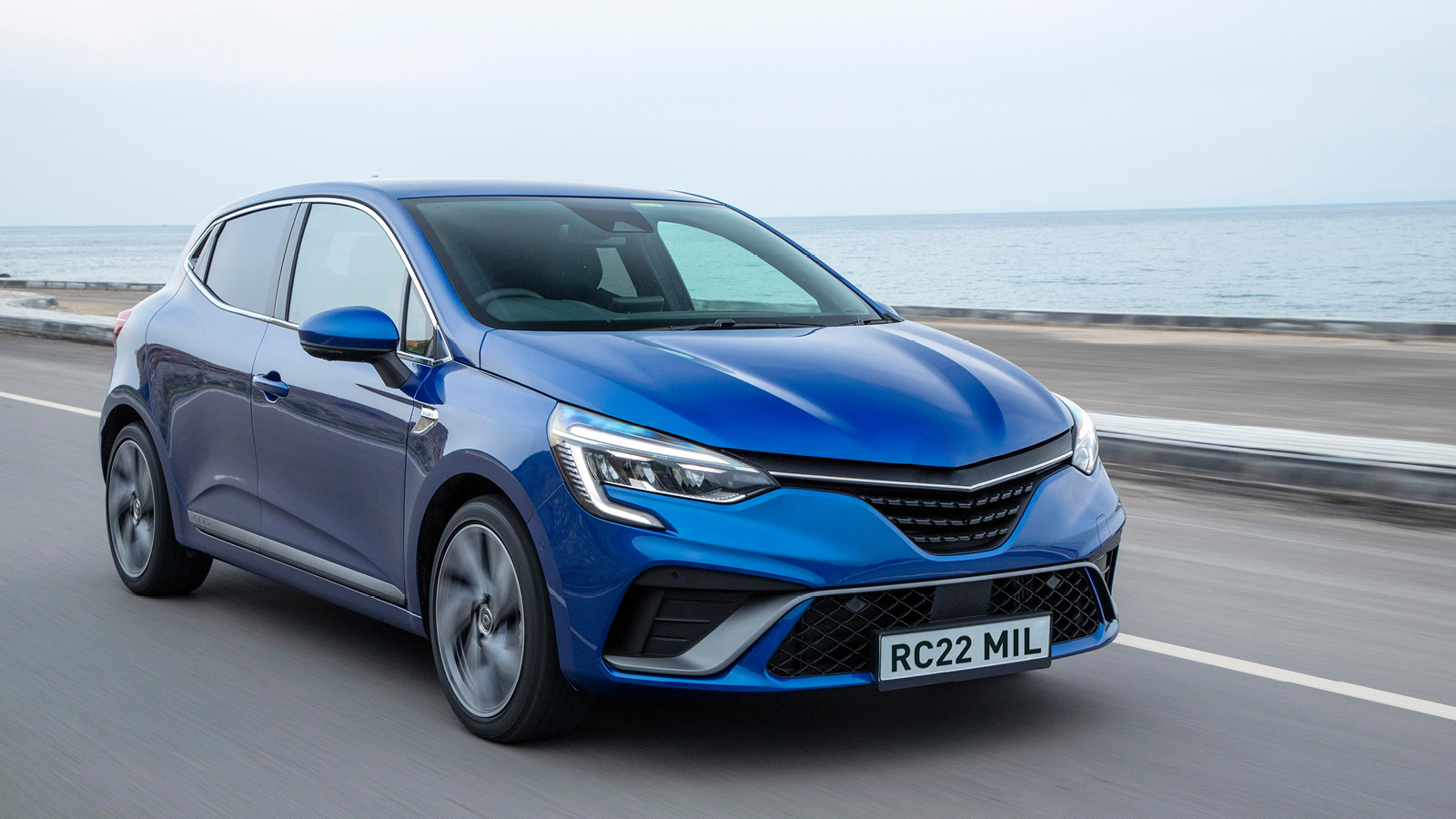 Photo of a blue car on a road next to the sea